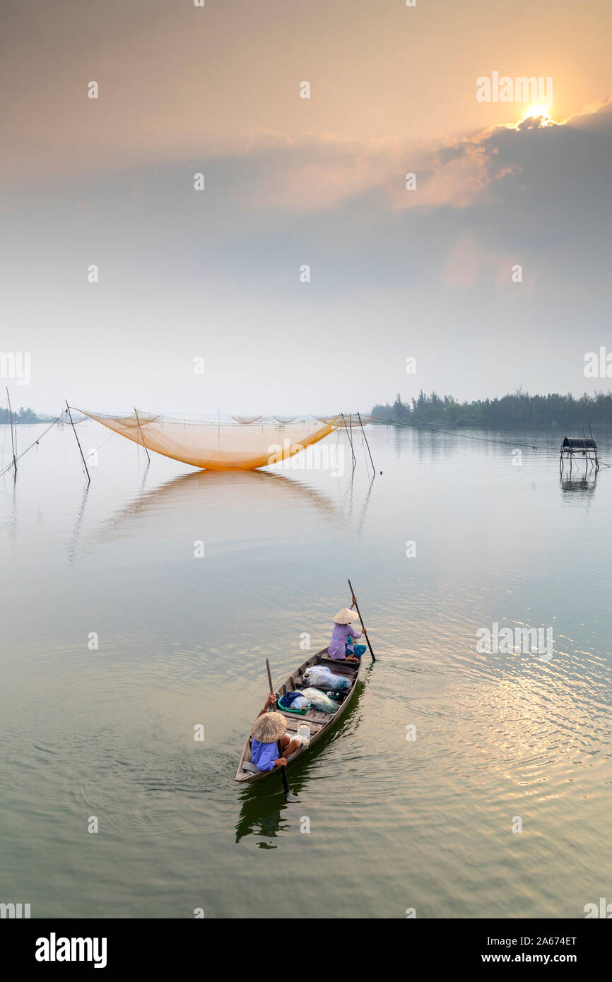 Fishermen row towards fishing nets at sunrise, Thu Bon River, Quang Nam Province, Vietnam Stock Photo