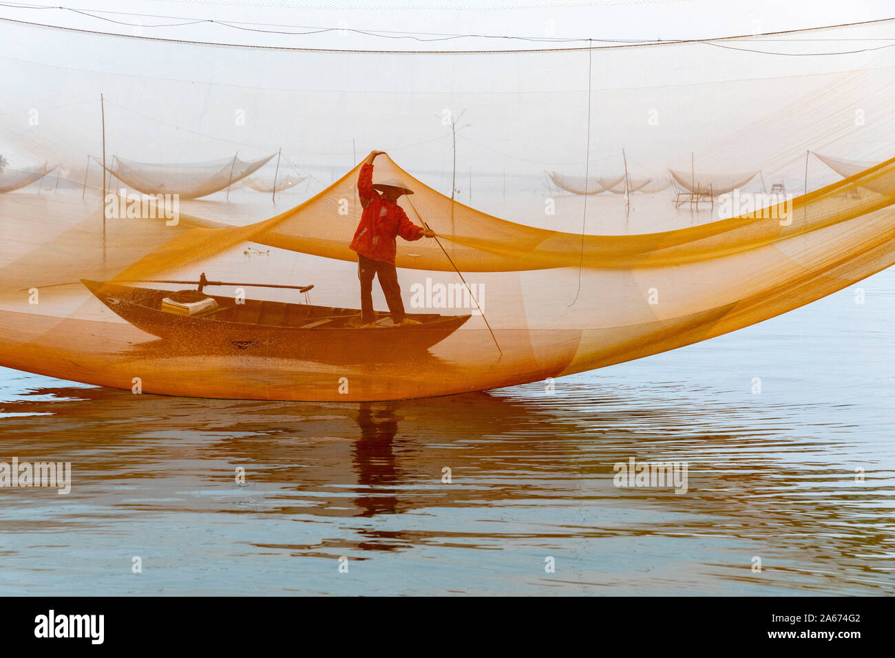 Fisherman working on the nets at sunrise, Thu Bon River, Quang Nam Province, Vietnam Stock Photo