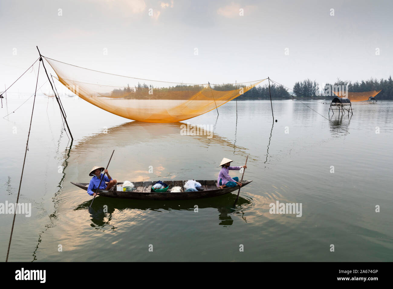 Fishermen row around fishing nets at sunrise, Thu Bon River, Quang Nam Province, Vietnam Stock Photo