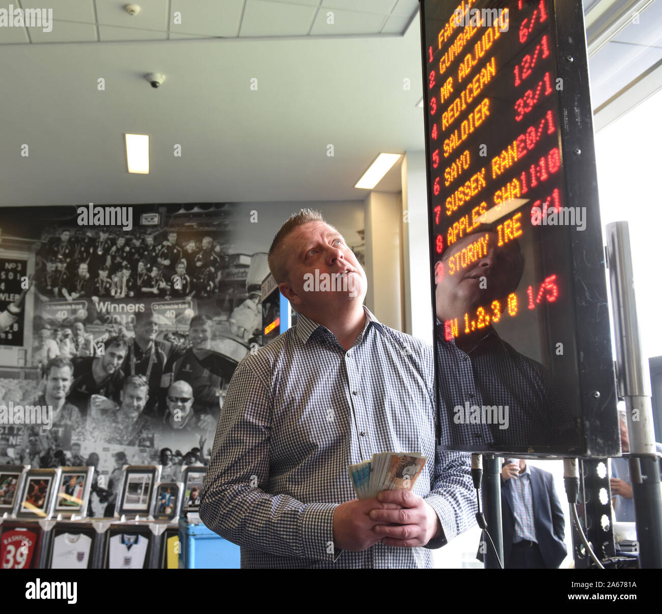 Bookmaker bookie checking the race odds on electronic board Uk Stock Photo