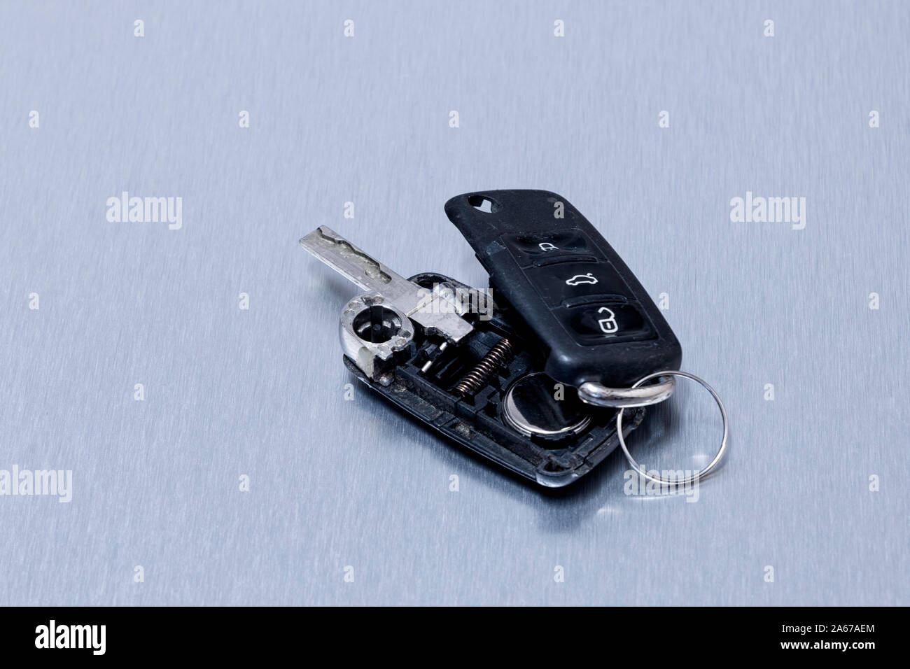 Broken or damaged car key fob on aluminium background. Repair of broken or damaged remote key fob of any vehicle car service.- Image Stock Photo