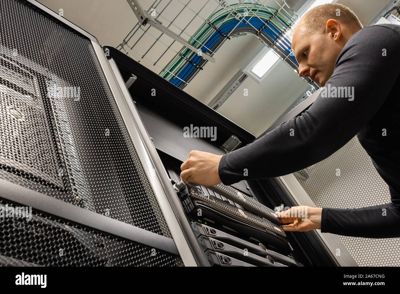 Male IT Technician Installing Server At Datacenter Stock Photo