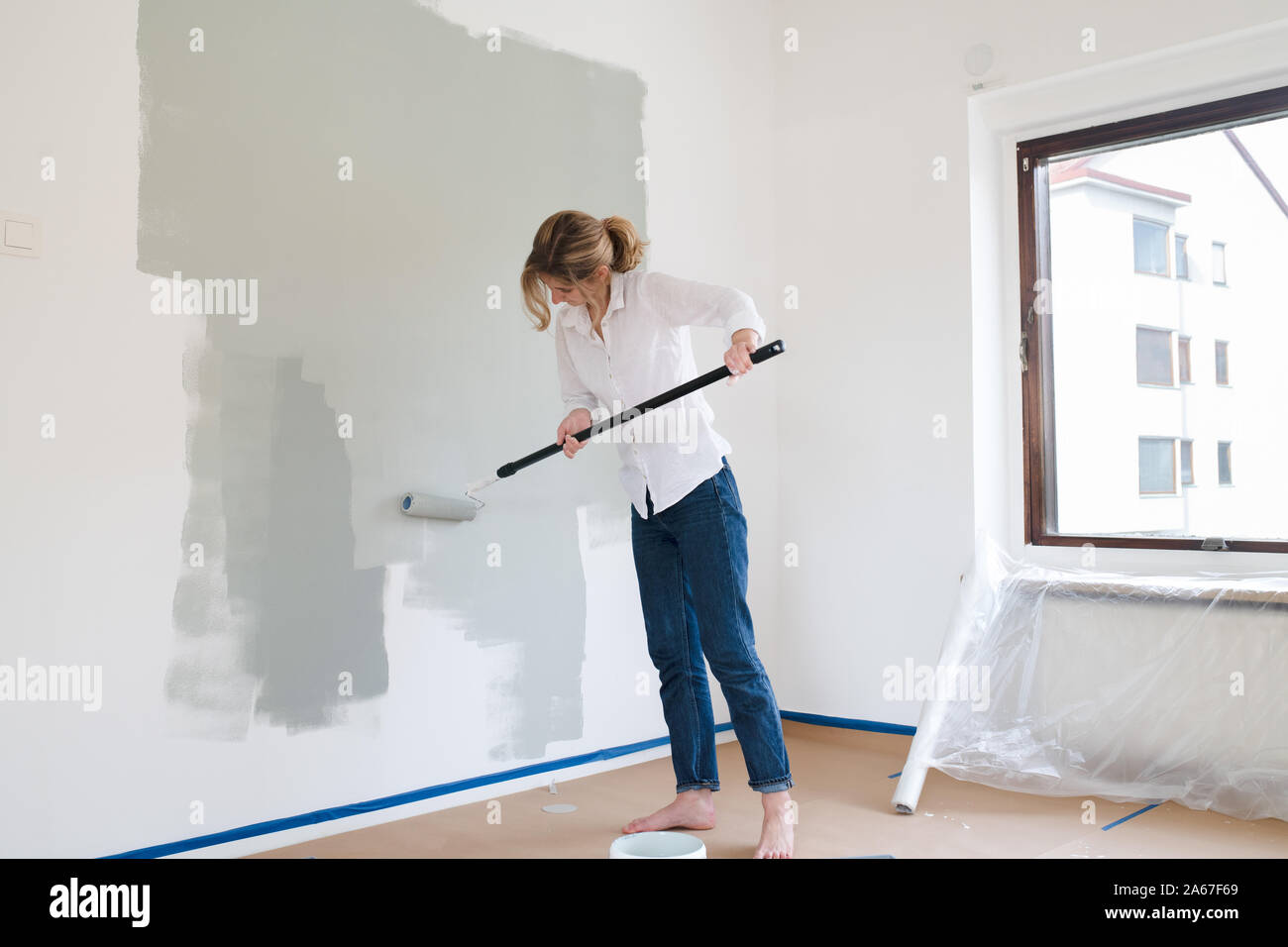 Woman rolling gray paint onto wall Stock Photo Alamy