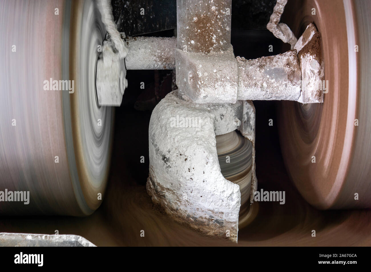 millstones of industrial melanger grind and mix cocoa and other ingredients in the process of making chocolate, blurry in motion Stock Photo