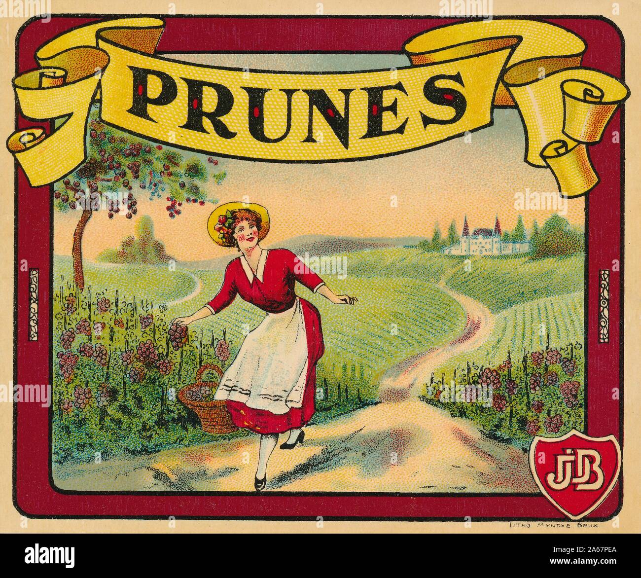 Label from a box or crate of 'Prunes, ' with an image of woman picking grapes in a rural setting with a chateau in the background, and with the initials 'JDB' intertwined on a shield in the lower right corner, likely produced in France, 1915. () Stock Photo