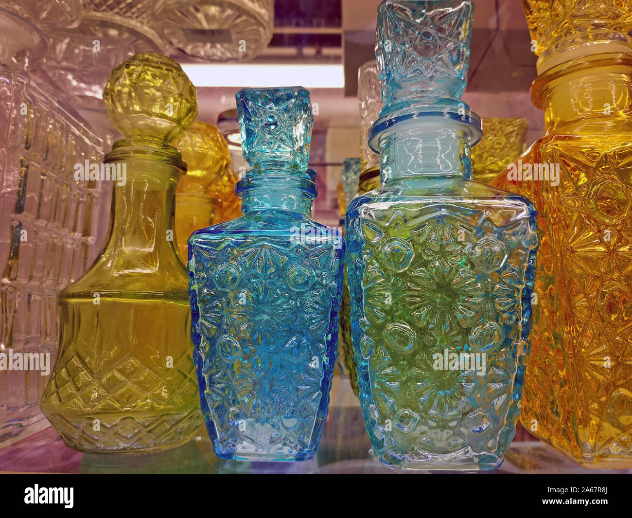 Glass decanters on a store shelf. Yellow and blue glass decanters of various shapes are sold