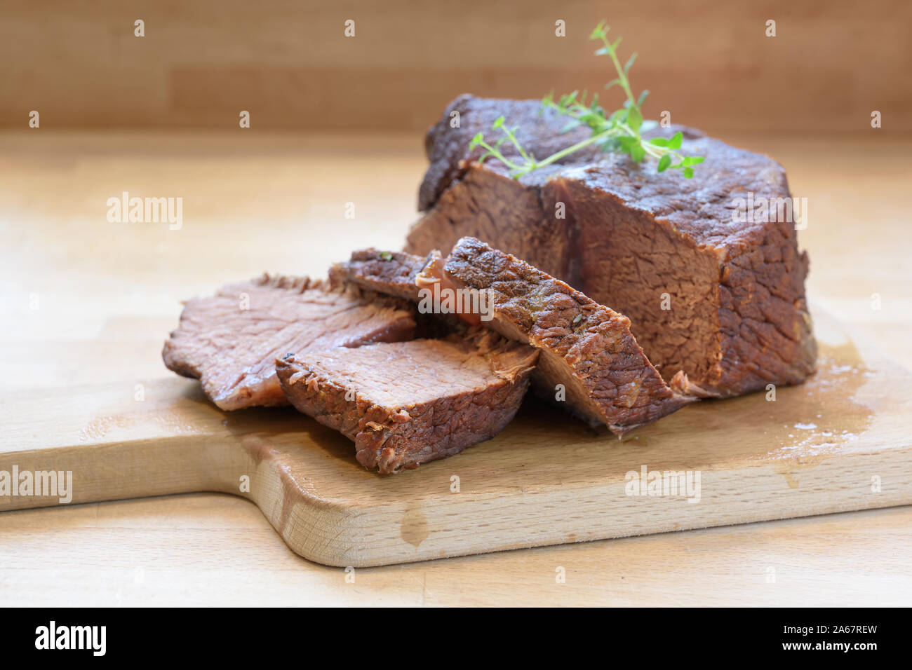 Slices of roast beef, ready braised in red wine with thyme garnish on a wooden table for a festive dinner like boeuf bourguignon, copy space, selected Stock Photo