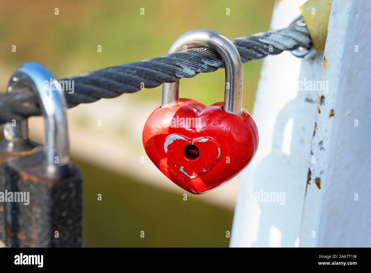 Red lock hang on a cable on a bridge. Symbol of eternal love and
