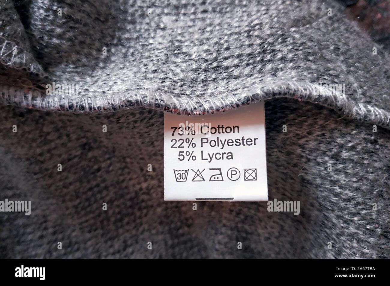 Wrong side of a gray dress made of wool, the composition is specified: cotton, polyester and lycra. Fabric composition clothes label on gray texture b Stock Photo