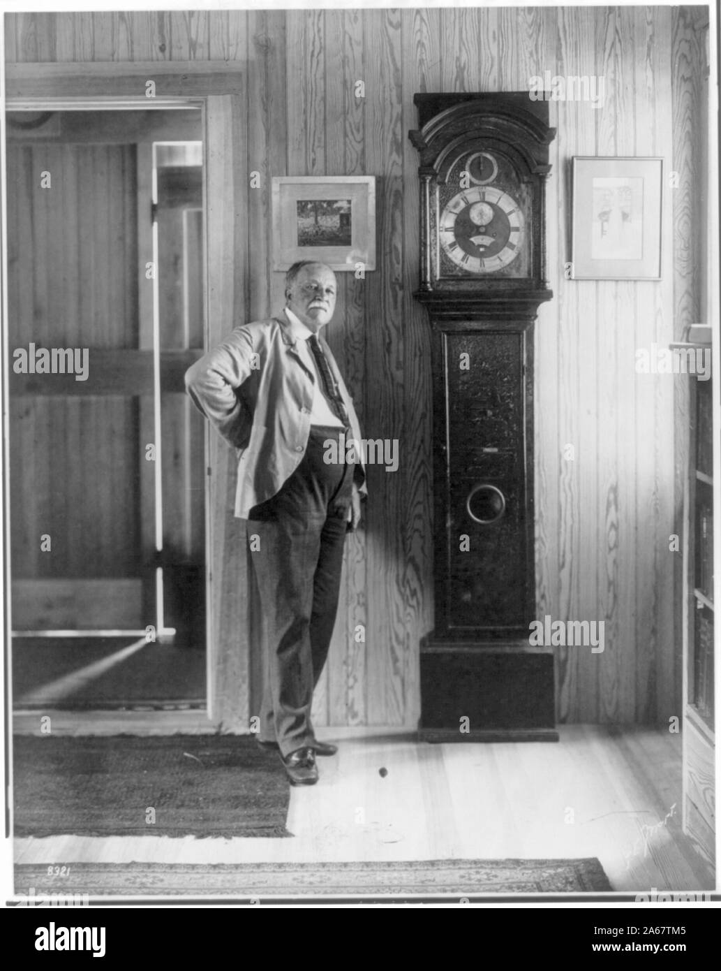 William Dean Howells, 1837-1920, full length portrait, facing right, standing by grandfather clock Stock Photo