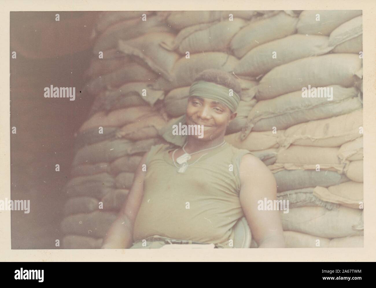 Half length portrait of African-American soldier wearing bandanna and dog tags, with sandbags in the background, in Vietnam during the Vietnam War, 1970. () Stock Photo