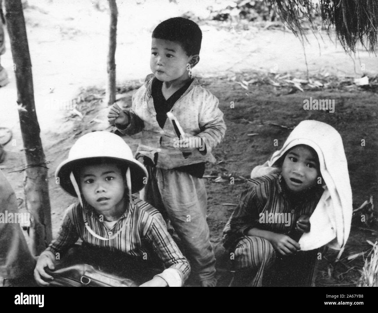 High angle shot of three of Vietnamese children, one wearing a pith ...