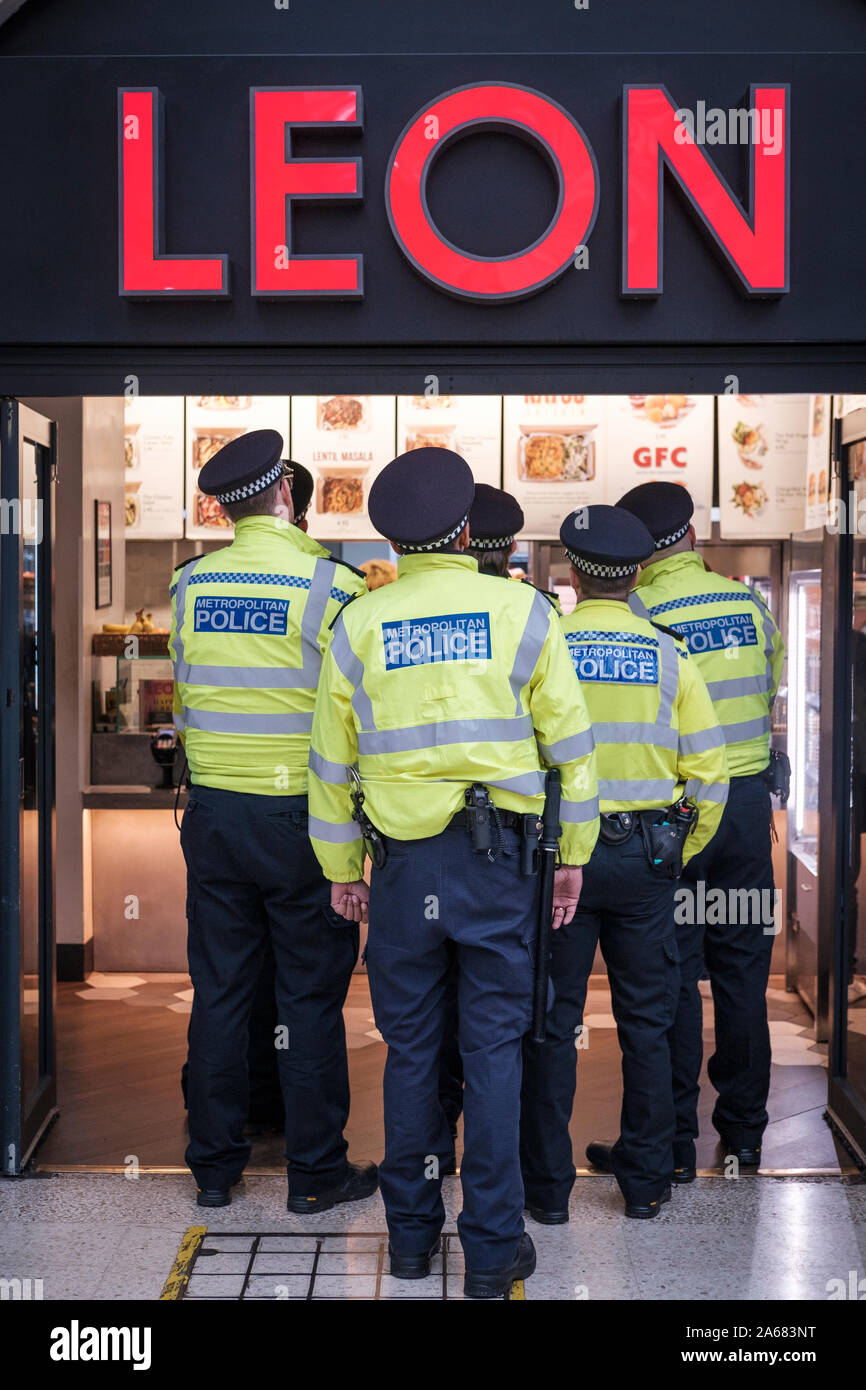 London,UK. Metropolitan police officers stand on queue at fast food restaurant Stock Photo