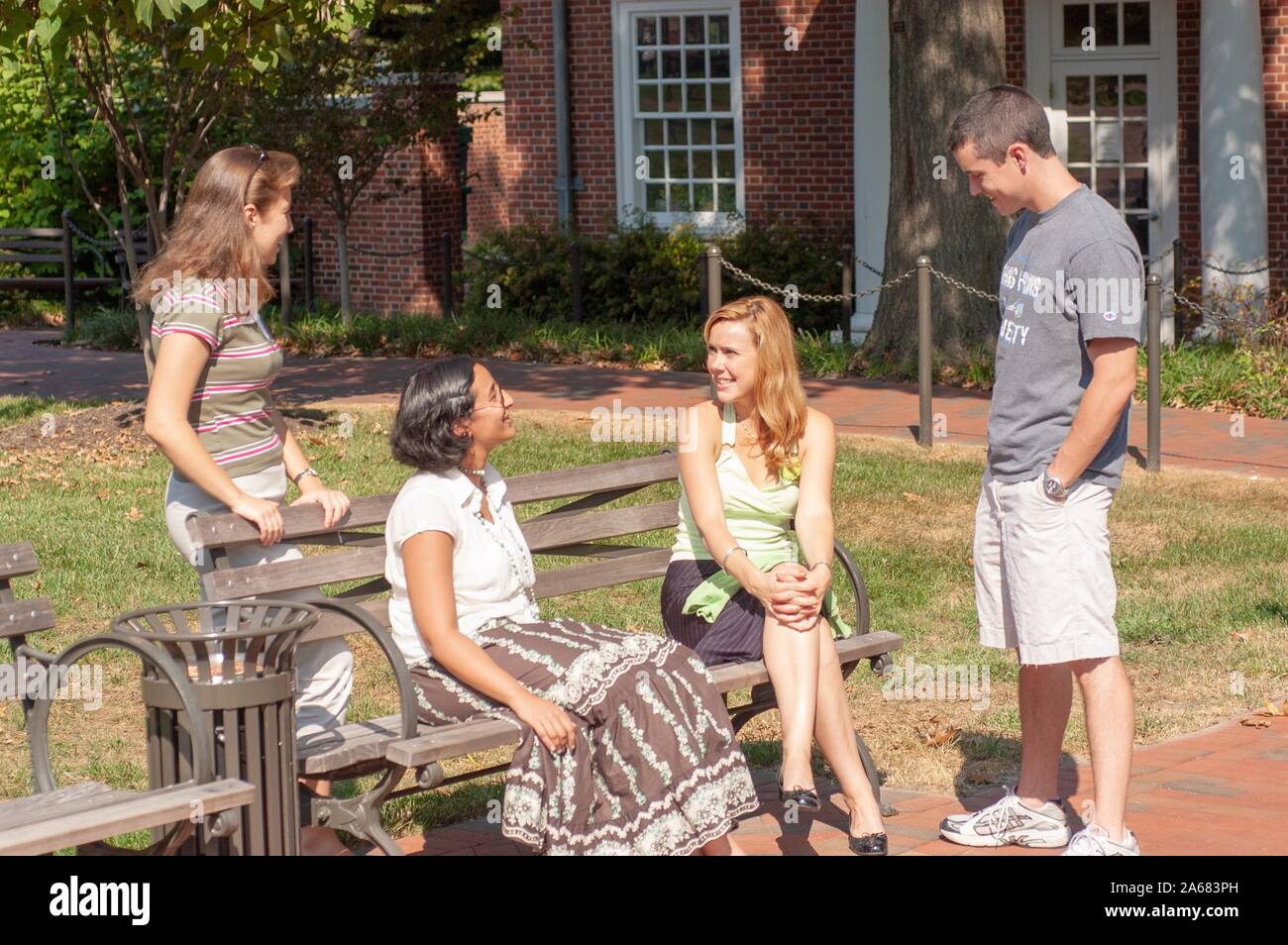 Students, outside on a sunny day, chatting while sitting on benches and standing nearby, on the grounds of the Johns Hopkins University, Baltimore, Maryland, September 19, 2005. From the Homewood Photography Collection. () Stock Photo