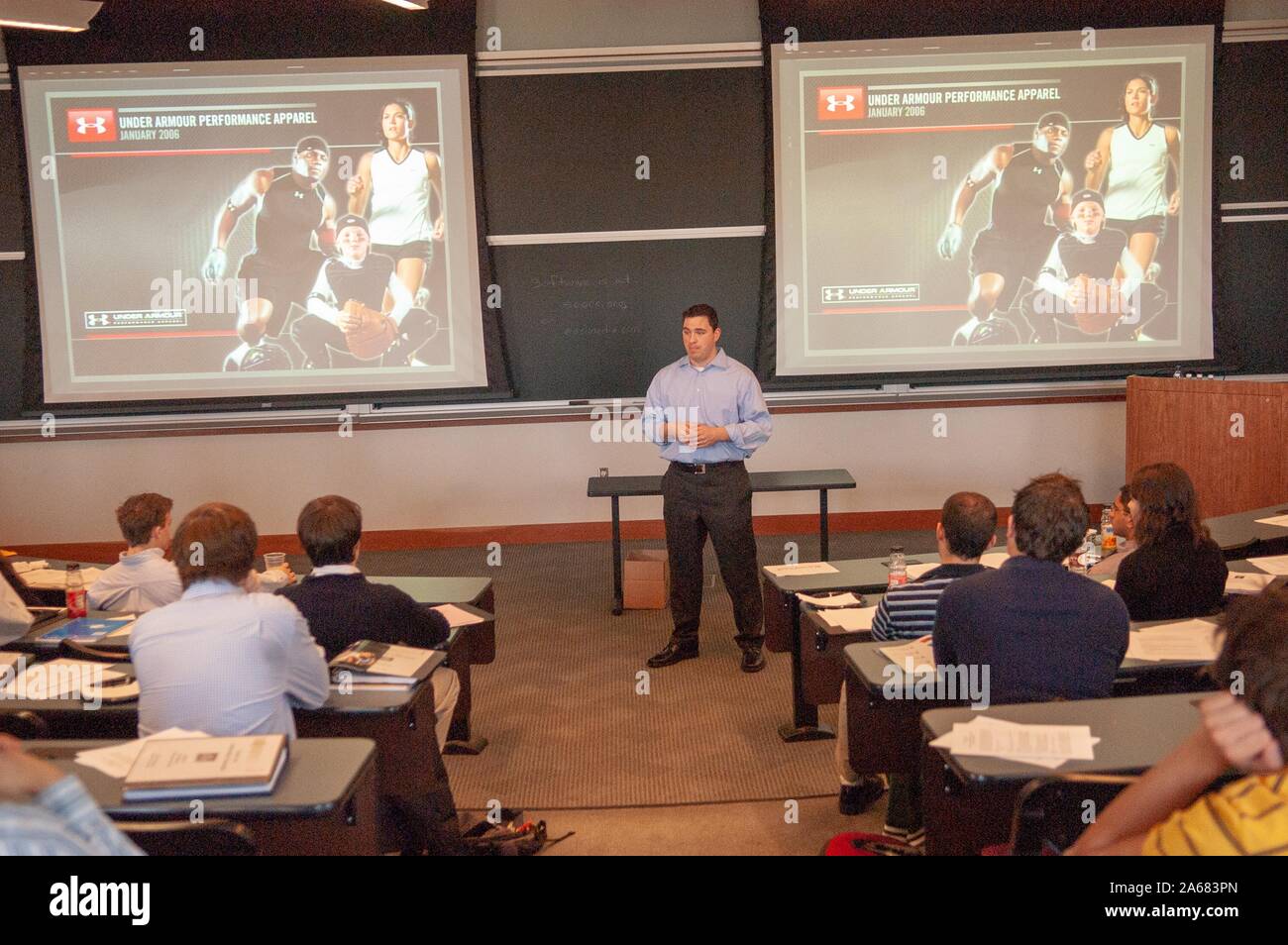 Wide shot of founder Kevin Plank standing in a classroom, in front of two screens advertising 'Under Amour Performance Apparel,' at the Johns Hopkins University, Baltimore, Maryland, January 12, 2006. From the Homewood Photography Collection. () Stock Photo