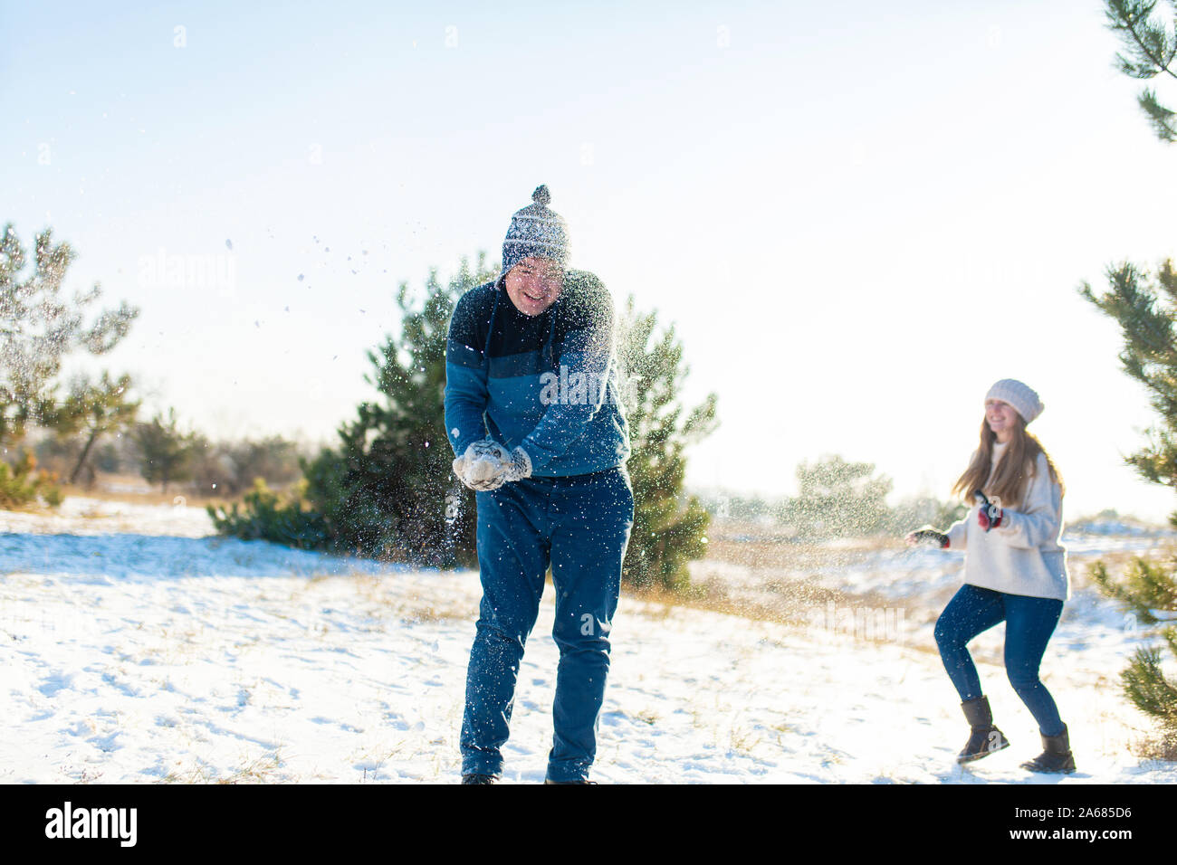 Loving couple play snowballs in winter in the forest. Throw each other ...