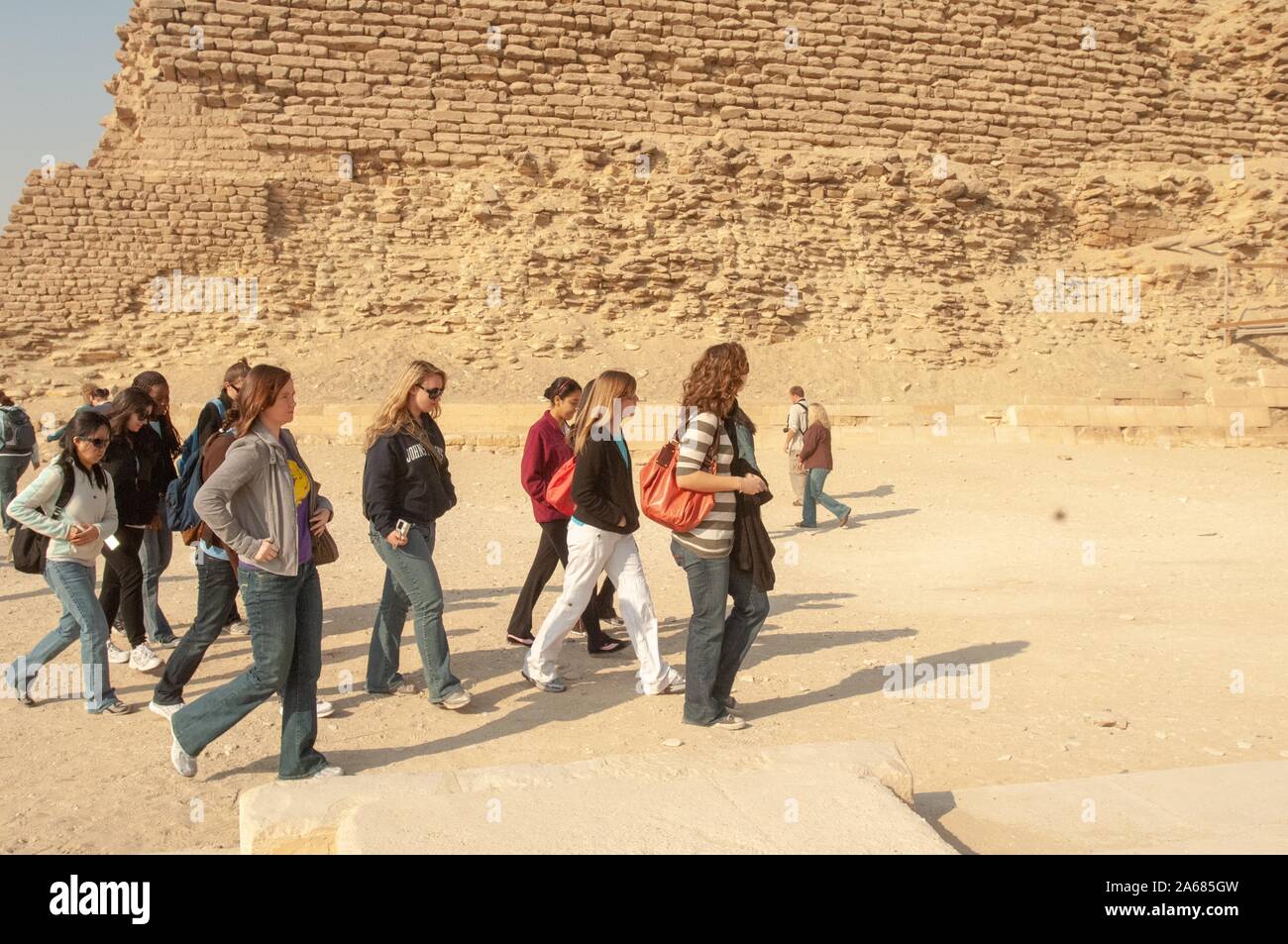 A group of students from the Johns Hopkins University in Baltimore, Maryland, outside on a sunny day, walking near the crumbling base of a pyramid, Giza, Egypt during a study abroad program, January 6, 2008. From the Homewood Photography Collection. () Stock Photo