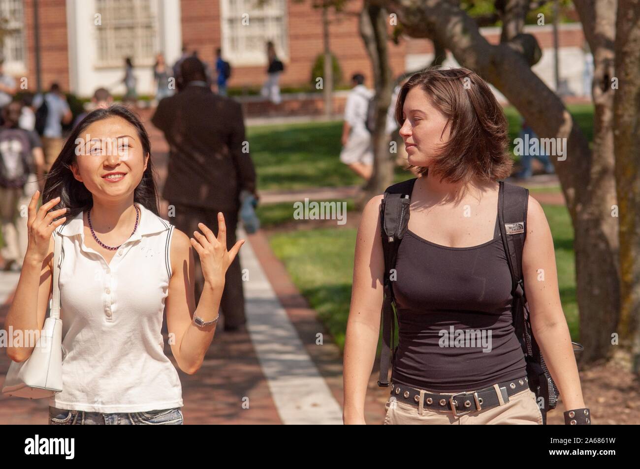 Two students, walking toward the camera, outside on a sunny day, on the grounds of the Johns Hopkins University, Baltimore, Maryland, September 19, 2005. From the Homewood Photography Collection. () Stock Photo