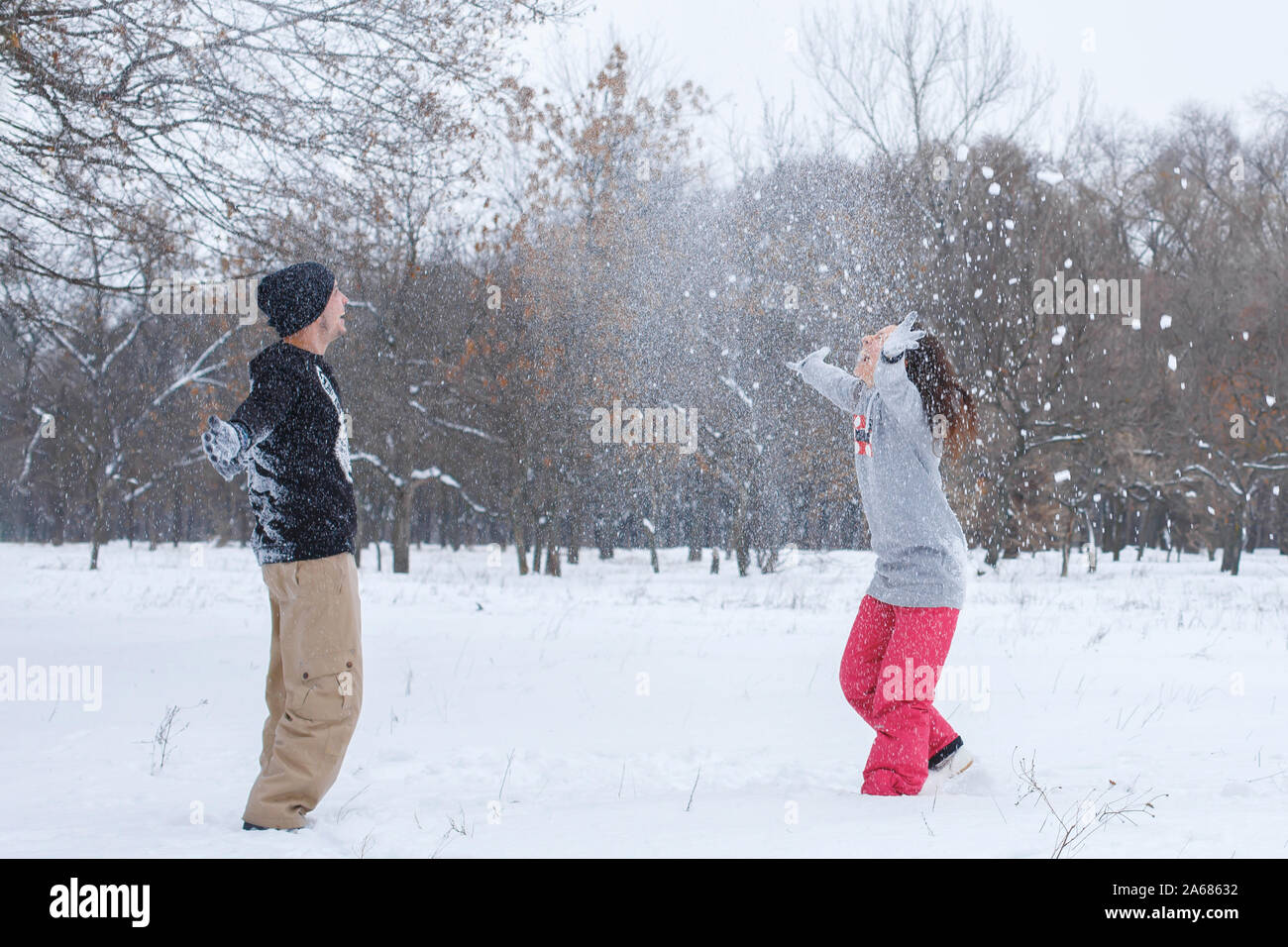 Loving couple having fun, laughing, playing and throwing snowballs in a ...