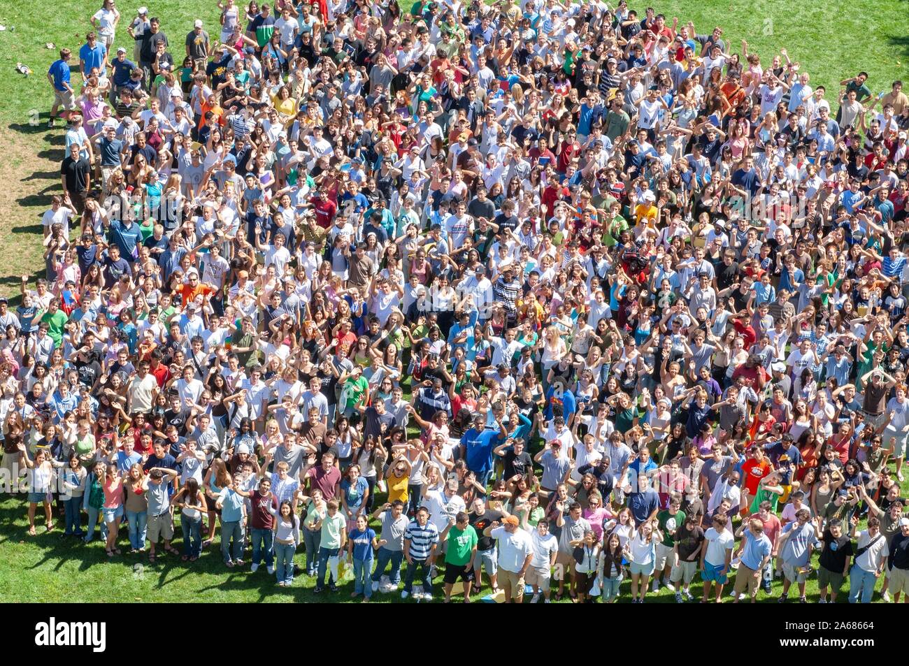 Bird's-eye view of a crowd, standing close together in a grassy area on a sunny day during a college orientation week event, and looking up toward the camera, at the Johns Hopkins University, Baltimore, Maryland, September 4, 2006. From the Homewood Photography Collection. () Stock Photo