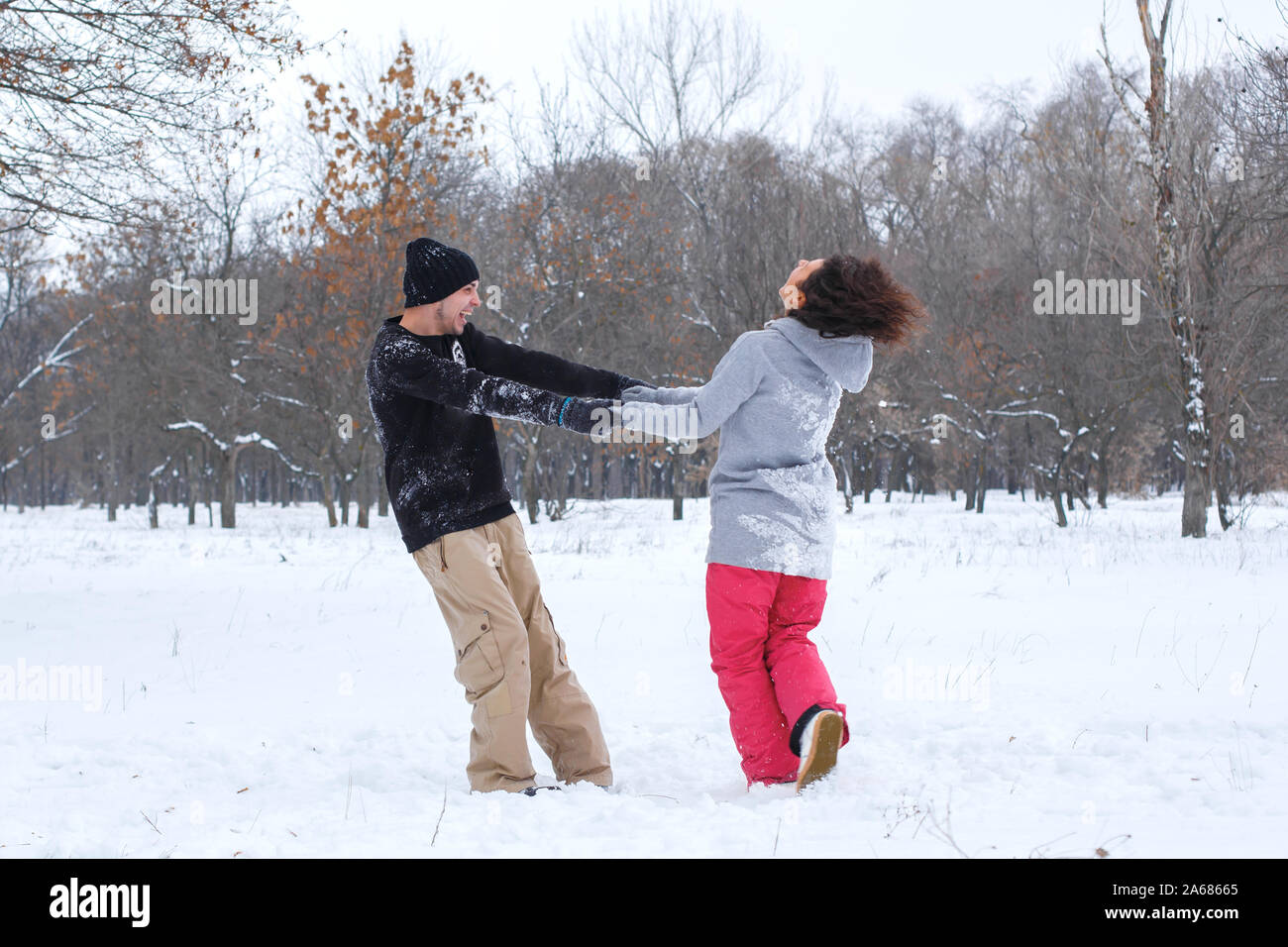 Loving couple having fun, laughing, playing and throwing snowballs in a ...