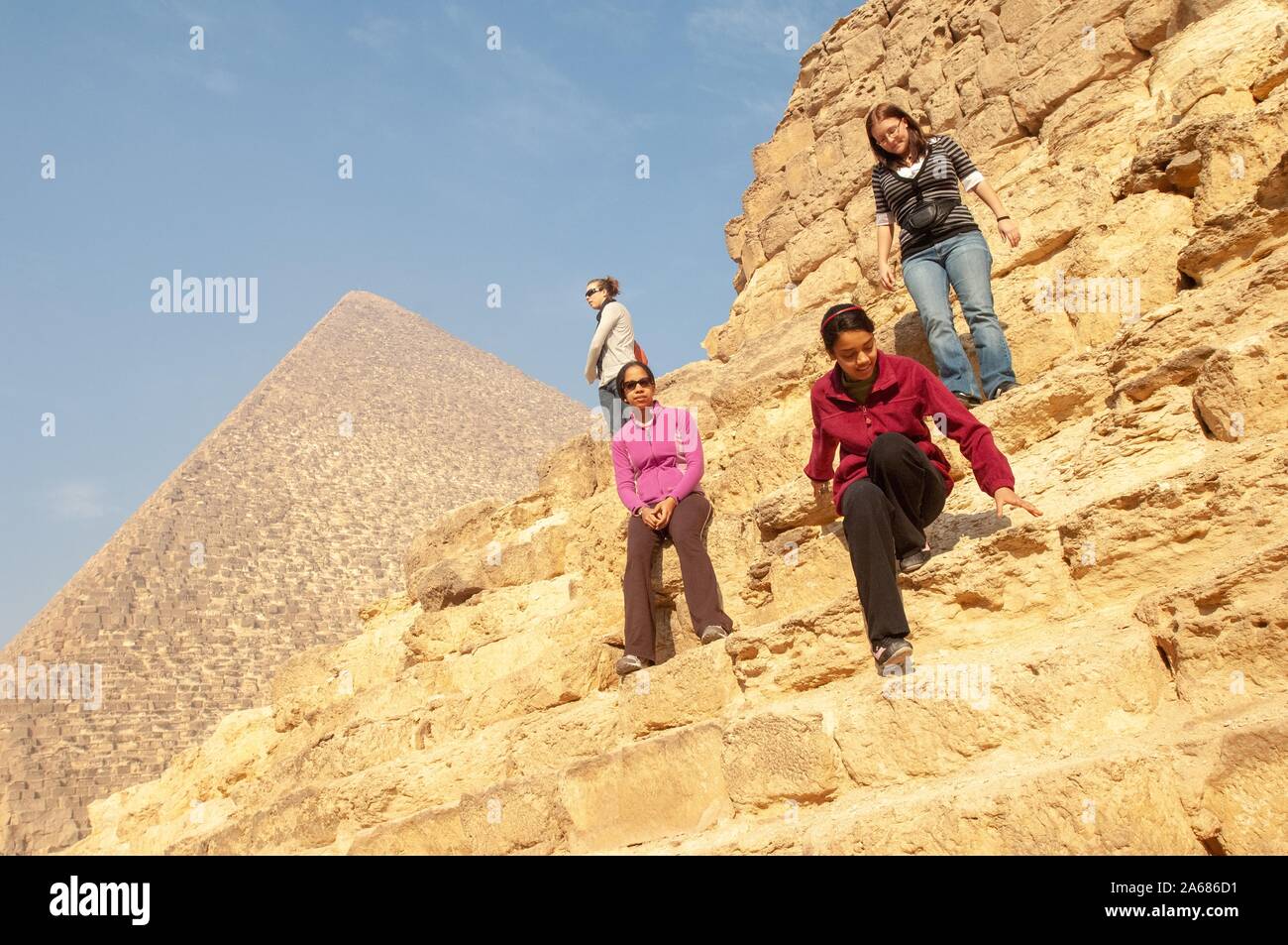 Several Johns Hopkins University students, outside on a sunny day, standing, leaning, and climbing on the blocks of a pyramid, with a second pyramid in the background, Giza, Egypt during a study abroad program, January 7, 2008. From the Homewood Photography Collection. () Stock Photo