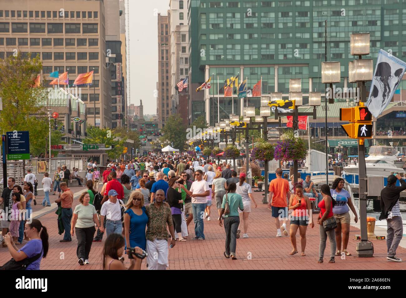 High-angle shot, on a sunny day, of crowds walking along a pedestrian wharf, with tall urban buildings in the background, Inner Harbor area, Baltimore, Maryland, September 6, 2009. From the Homewood Photography Collection. () Stock Photo