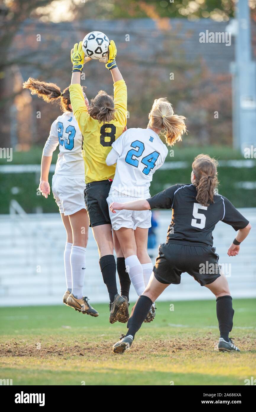 Full-length shot of two Johns Hopkins University Women's Soccer players, leaping in tandem with an opposing goalie who reaches for the ball, during a Centennial Conference semifinals match with Haverford College, November 7, 2009. From the Homewood Photography Collection. () Stock Photo