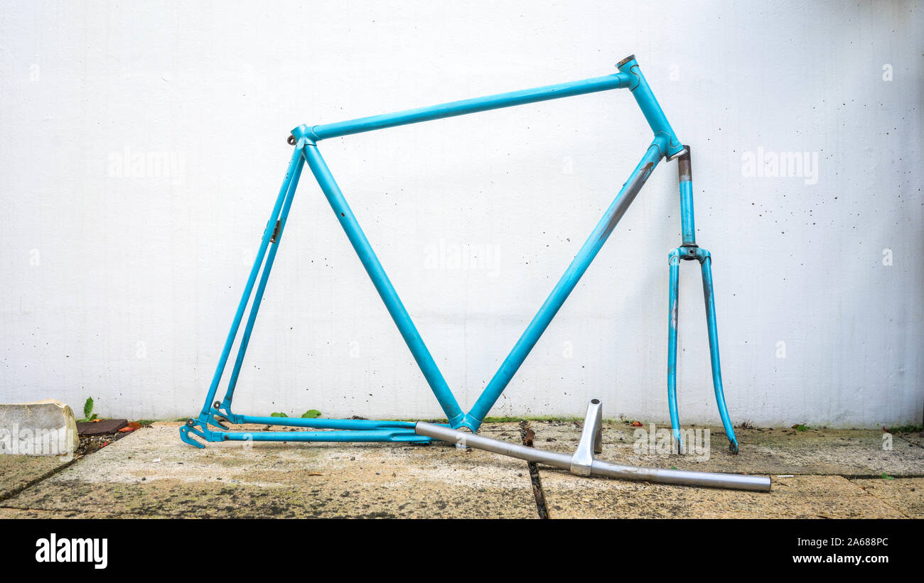 Blue retro bike frame in fornt of a white wall ready for restoration Stock Photo