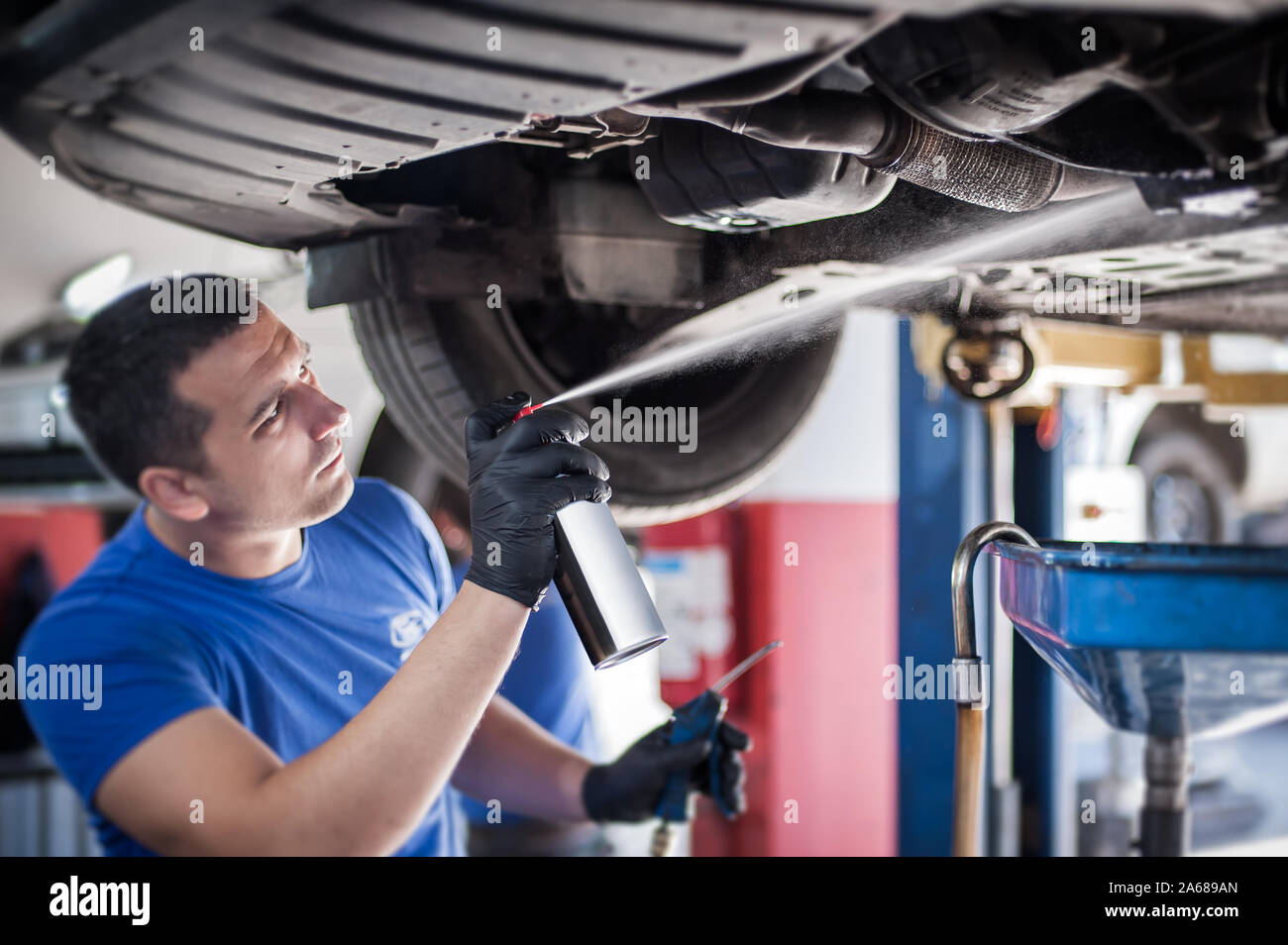 Car master mechanic repairer lubricates the screws with a machine parts cleaner oil dirt grease