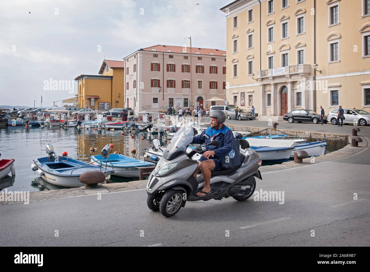 A middle aged man on a three wheel motorcycle rides along the Adriatic coastline in Piran, Slovenia. Stock Photo