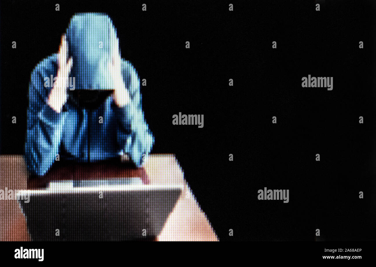 Screen shot: Hooded character looking at the computer, focused on the task. Low-key, copy-space, isolated. Stock Photo