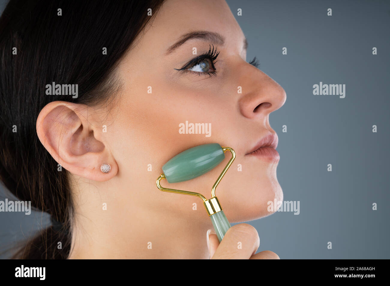 Young Woman Using Jade Roller On Her Face Stock Photo