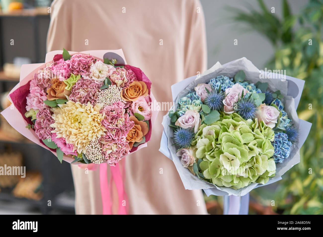 Two Beautiful bouquets of mixed flowers in womans hands. the work of the florist at a flower shop. Fresh cut flower. Stock Photo