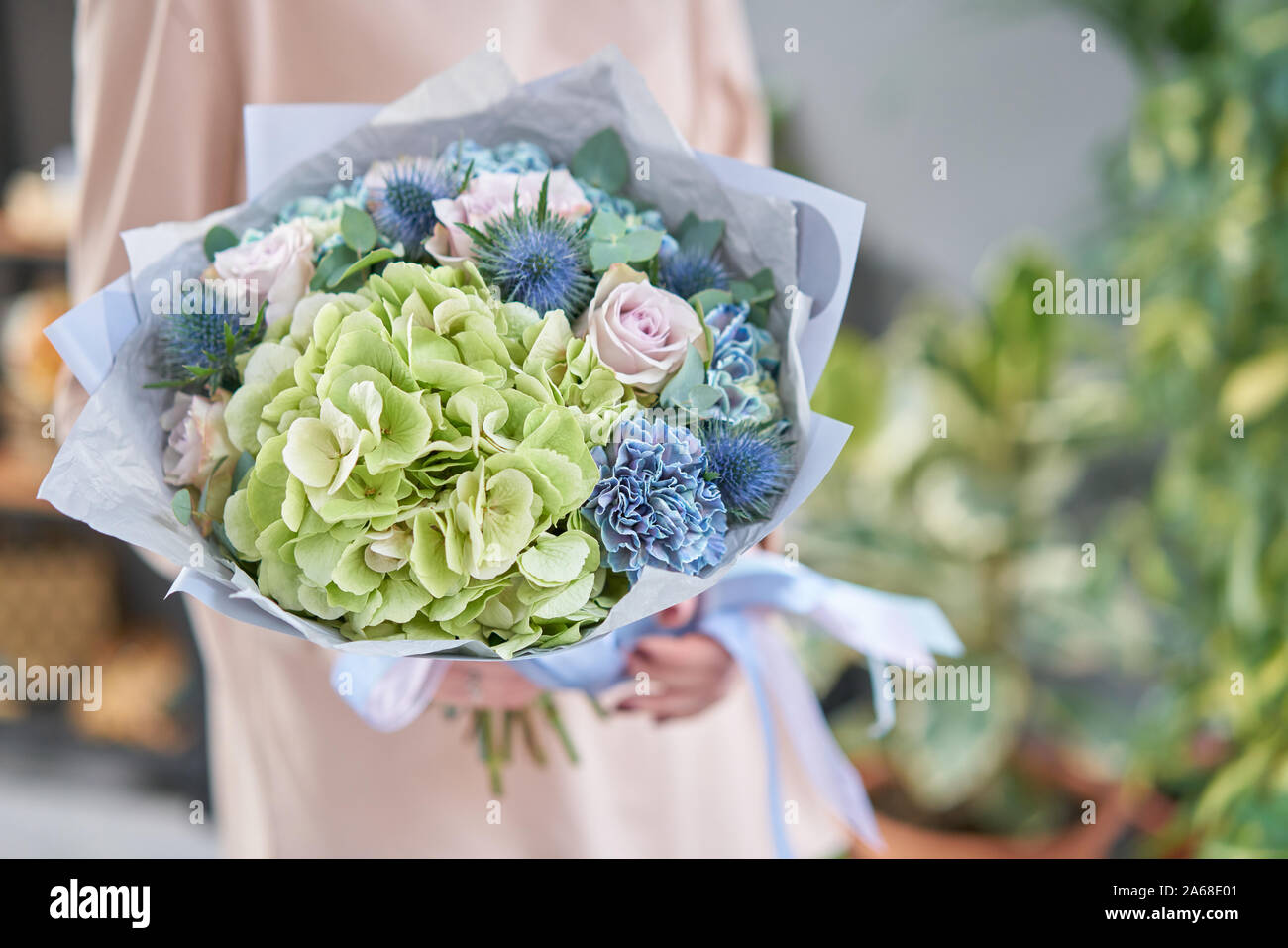 Beautiful bouquet of mixed flowers in womans hands. the work of the florist at a flower shop. Handsome fresh bouquet. Flowers delivery Stock Photo