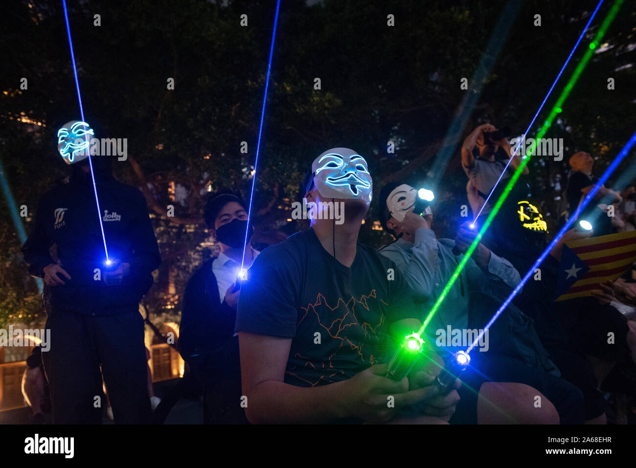 Protesters wearing masks use laser pointers as they take part during the Hong Kong Catalonia solidarity gathering at the Central district in Hong Kong. Stock Photo