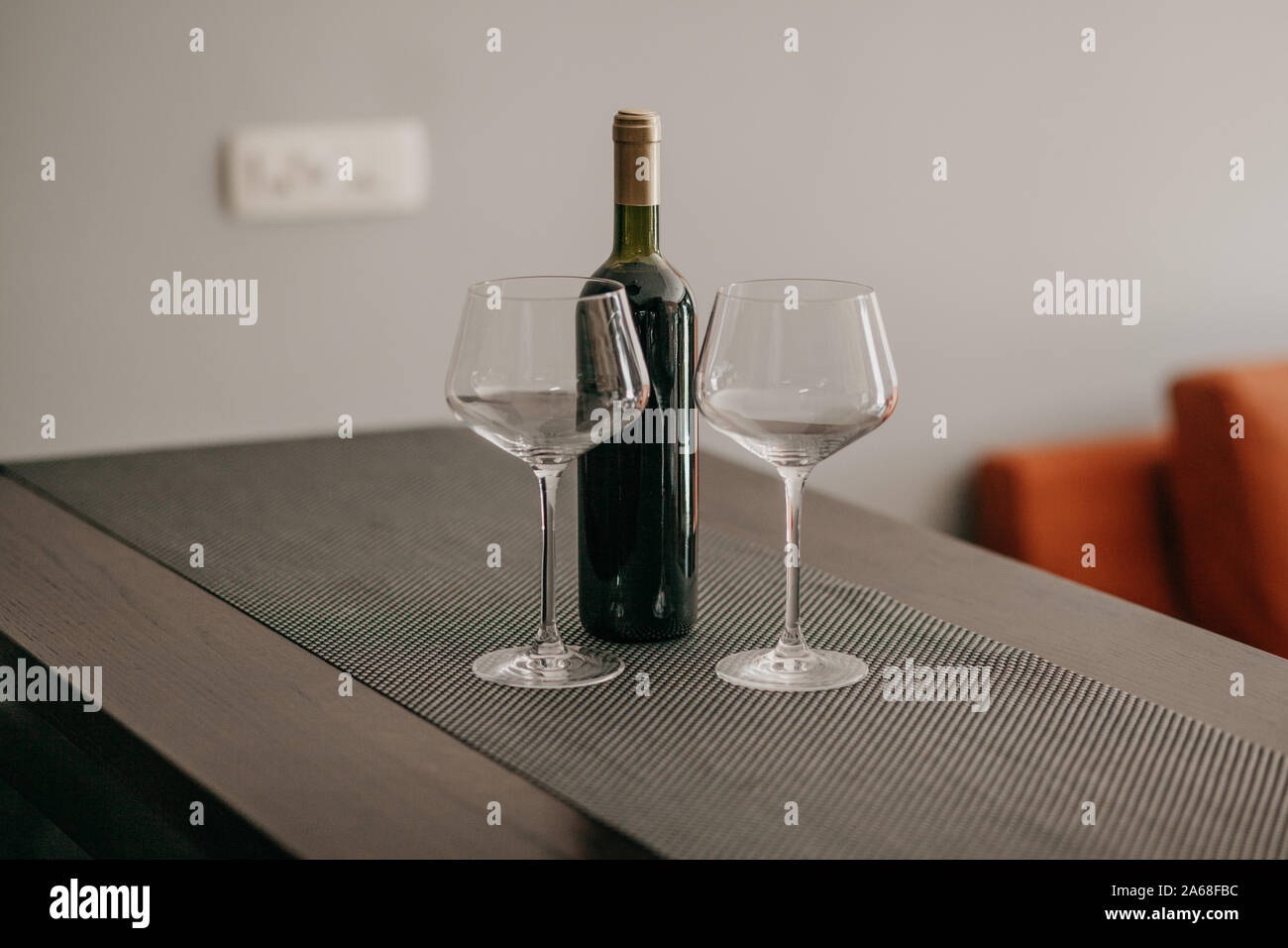 A bottle of red wine and two empty glasses on the table. Stock Photo