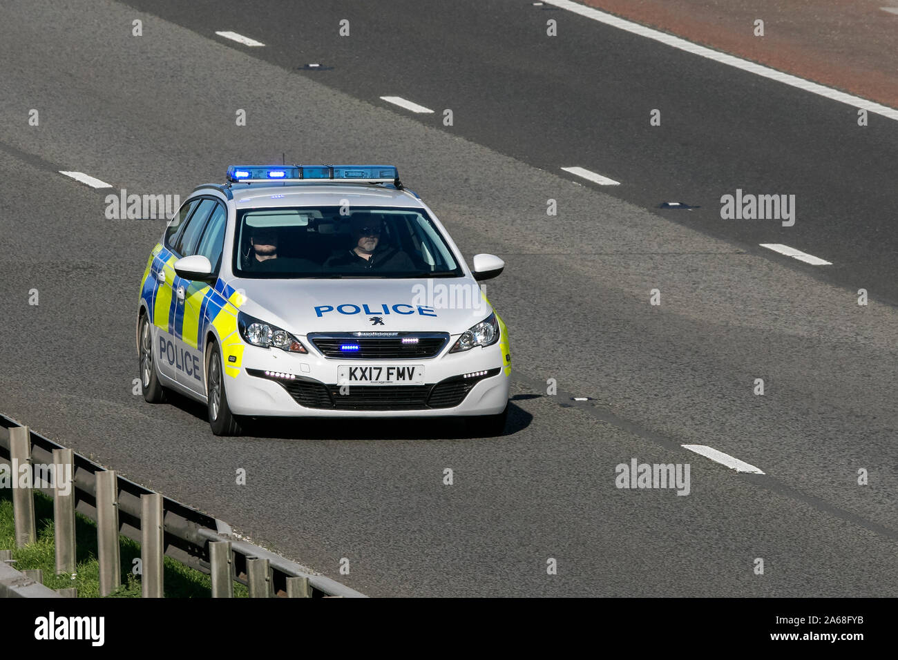 A police patrol vehicle, Peugeot 308 Access SW Blue HDI S/, traveling on the M6 motorway near Preston in Lancashire, UK Stock Photo