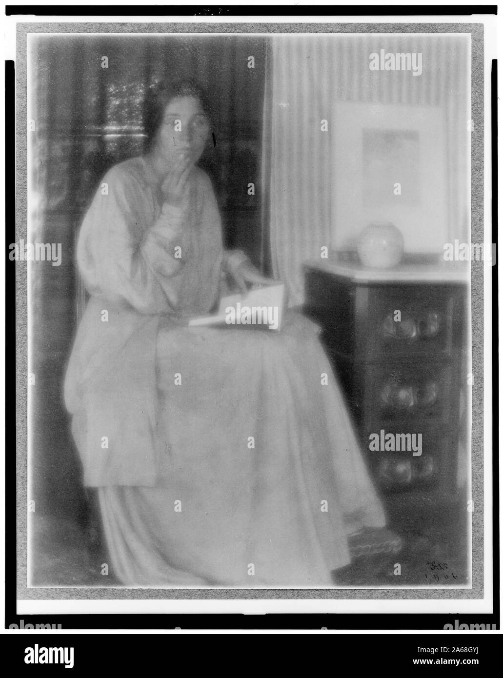 Woman (Beatrice Baxter Ruyl), in dress with open book in lap and hand to face, seated Stock Photo