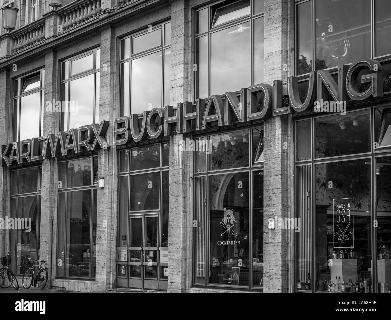Old Karl Marx bookshop at Karl Marx avenue in Berlin Friedrichshain, East Germany, former GDR, oblique view with letttering, black and white Stock Photo