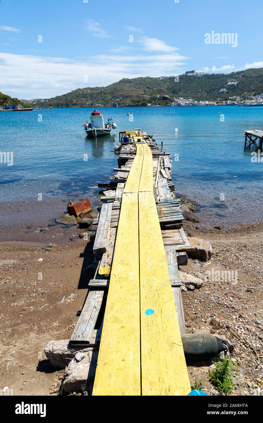 Rickety wooden pier, painted bright yellow, with fishing along the shore of Patmos, Greece.  An island in the Dodecanese surrounded by the Adriatic. Stock Photo