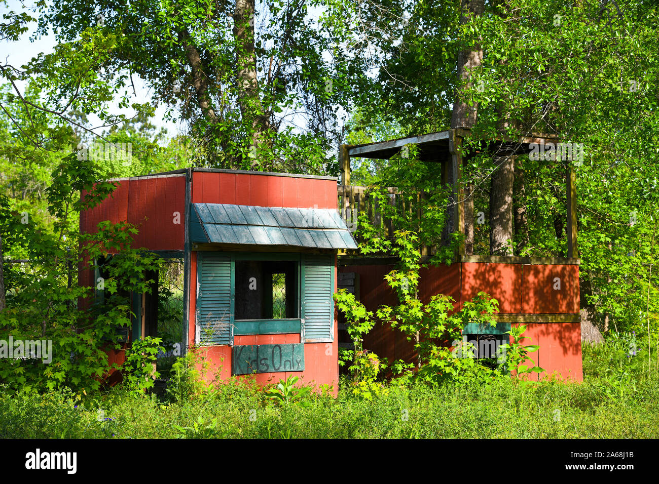 An Old Abandoned Kid's Playhouse sitting in an over grown yard. Stock Photo