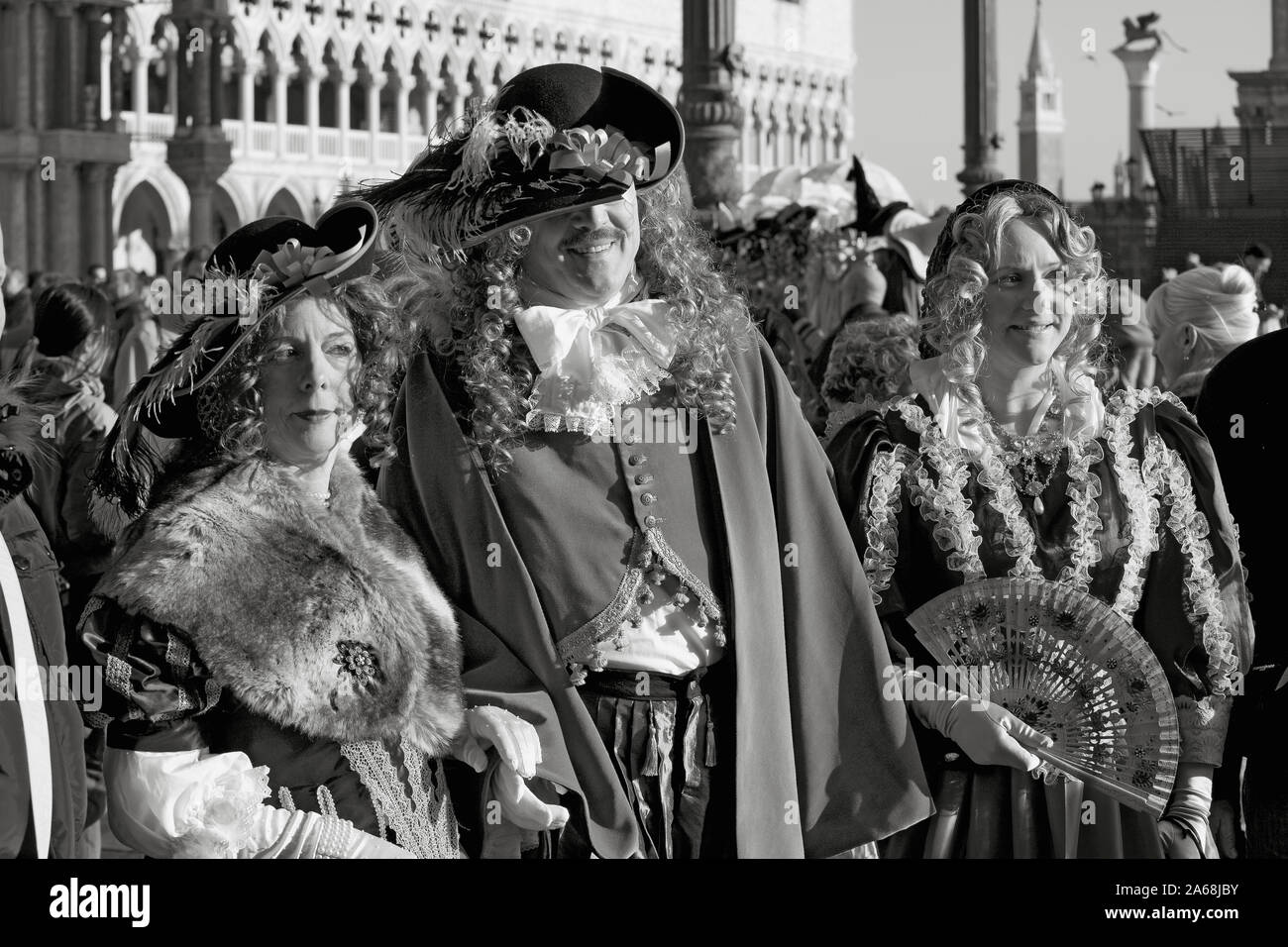 Piazza San Marco, Venice, Italy: three elegantly-costumed carnevale revellers in elaborate eighteenth century dress.  Black and white version Stock Photo