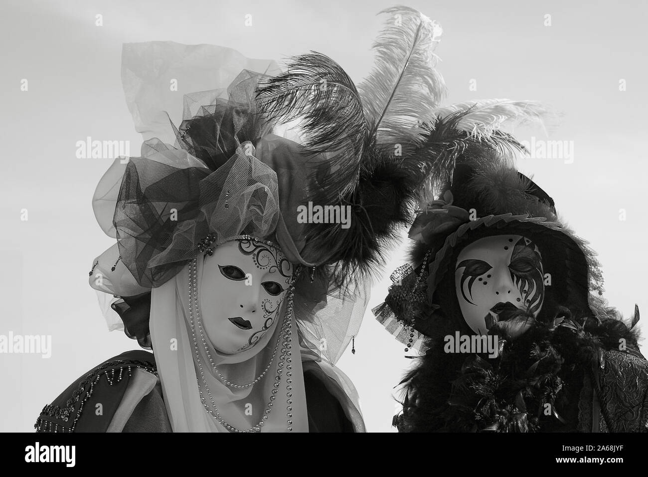 Close-up of two masked revellers posing for the camera on Molo San Marco, Venice, Italy.  Black and white version Stock Photo