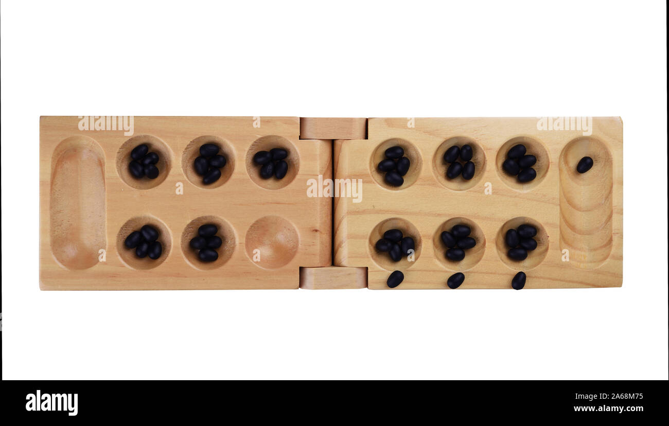Stones and wooden folding board for playing mancala. A hole for stones, a variant of the first move in the game. The concept of board games. Stock Photo