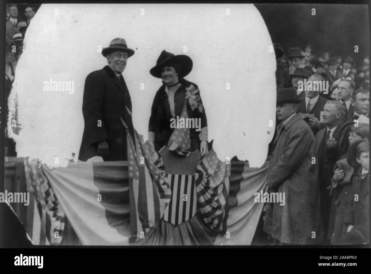 Woodrow Wilson, half length, standing, facing right; and his wife (Edith Bolling Galt), on flag-draped platform in front of crowd Stock Photo