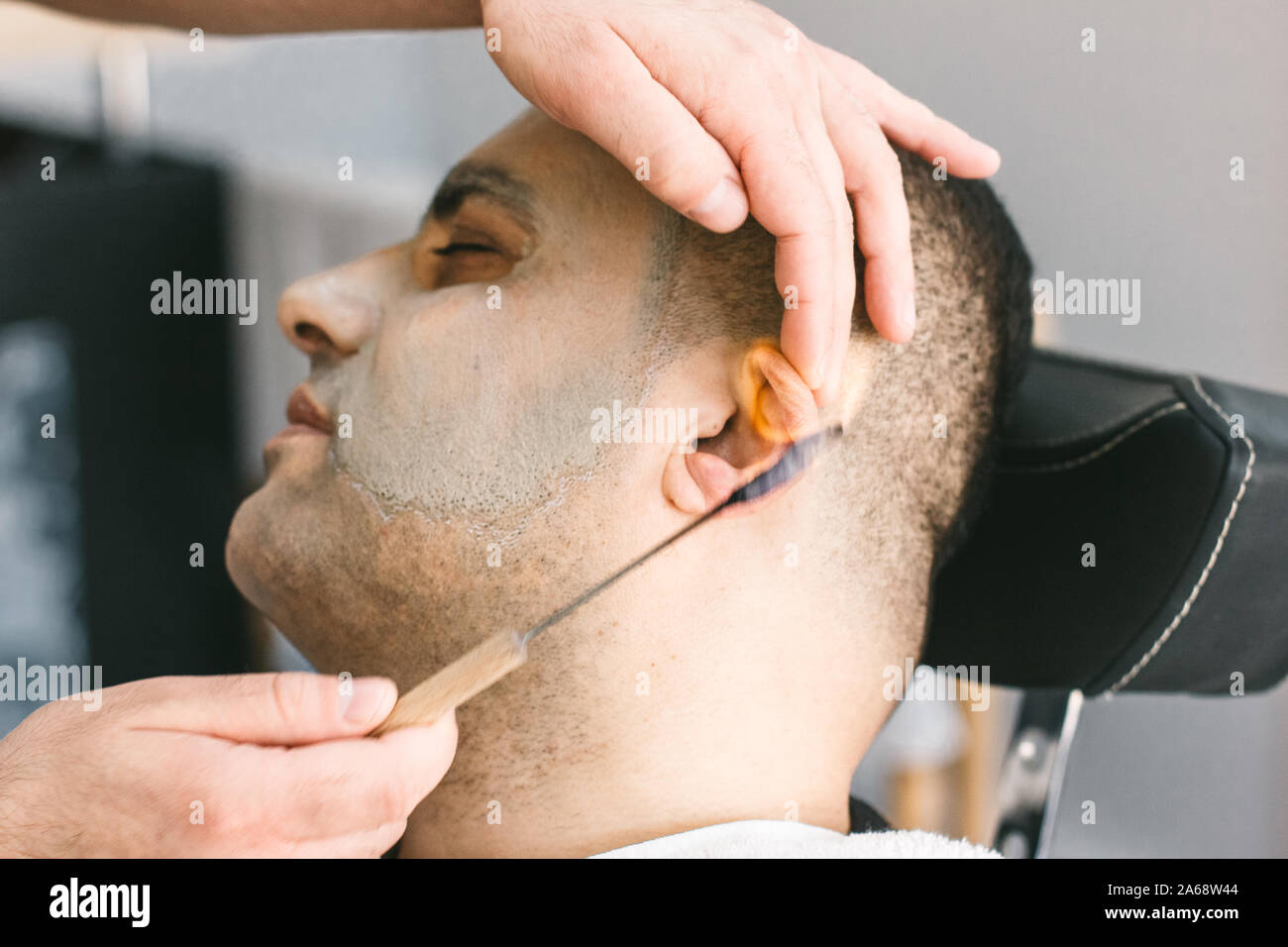 Hairdresser removes hair from the ears of man in a barber shop by burning fire. Stock Photo