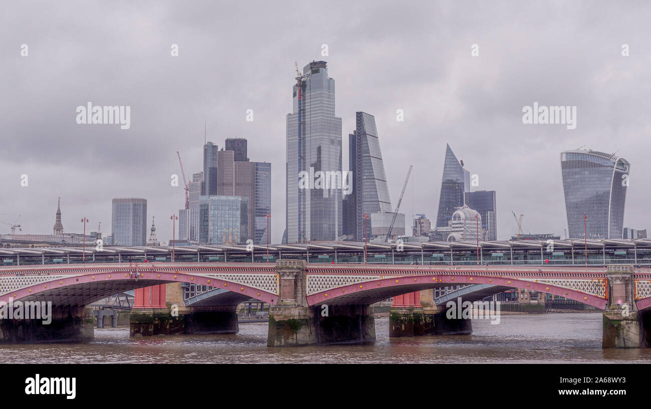 Blackfriars Bridge over the river Thames on a grey misty day with City of London office buildings in background. Stock Photo
