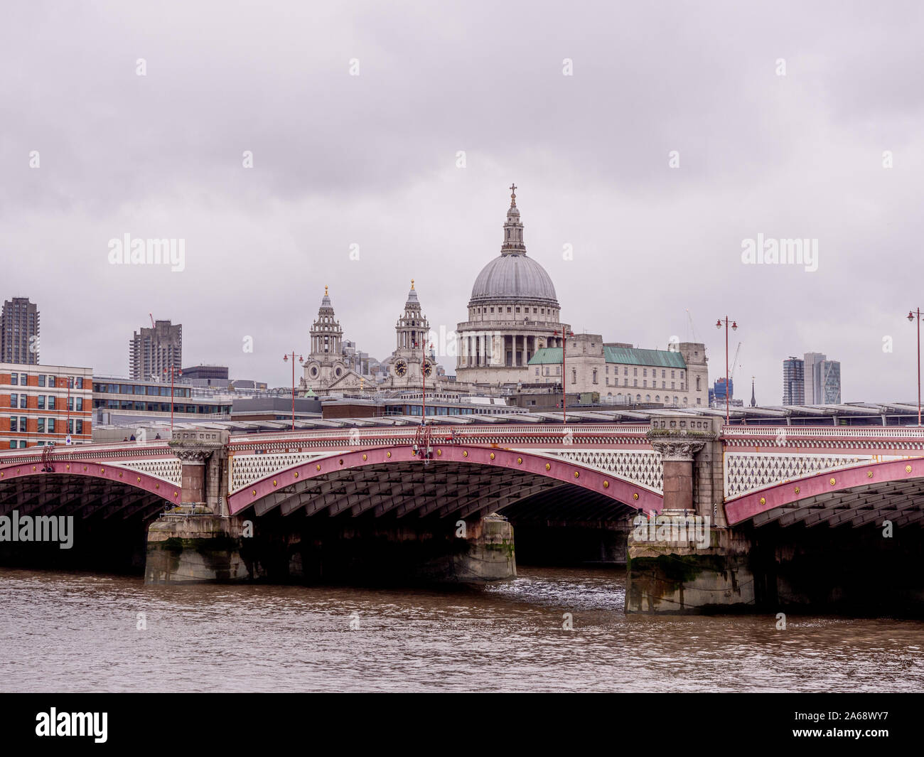 Blackfriars Bridge over the river Thames on a grey misty day with St Pauls, in background. Stock Photo