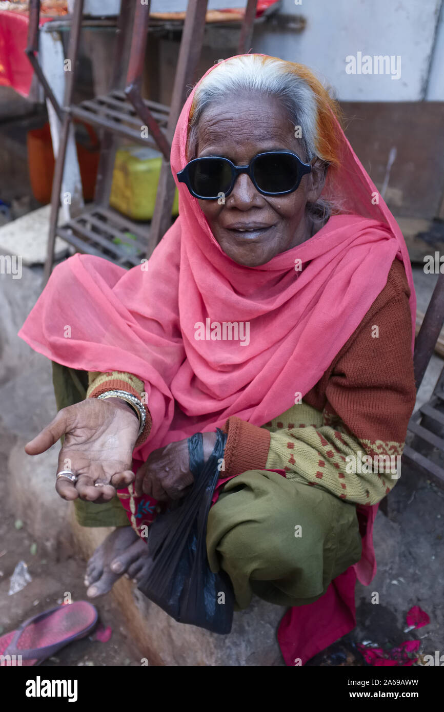 An elderly female beggar with black sunglasses (not blind) begging near ...